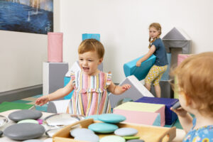 Three children playing with large colourful blocks.