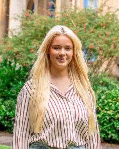 An adult with medium-light skin, long straight blonde hair, and a red and white striped shirt.