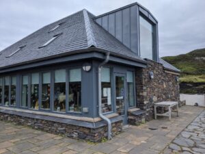 The entrance to the Atlantic Islands Centre. It is a two-storey building with rough stone walls, grey windows, and a grey tiled roof.