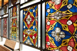 A display of brightly-coloured stained glass which features detailed floral designs.