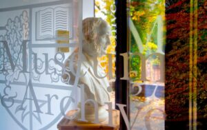 A marble bust of an older adult of European heritage is seen through glass windows at Heriot-Watt University. The adult has sideburns and short wavy hair.