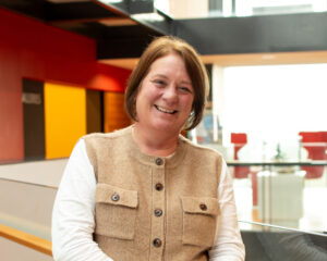 An adult with light skin, medium-length brown hair, and a brown cardigan.