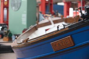 A large blue wooden boat with the name 'Katie' on display at the Scottish Maritime Museum.