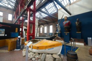Boats, barrels, and figureheads on display inside the Scottish Maritime Museum.