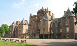 A large house with rough stone walls and pointed grey rooves.