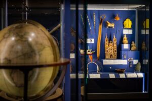 A display case of religious and cultural artefacts from across the world. In the foreground, out-of-focus, is a large globe.