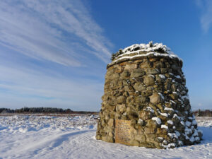 A large stone cairn in a snowy field.