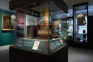 A glass display case in the middle of a room containing a display of historic medicines and tinctures.