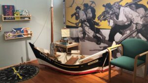 A model of a sailing boat sits in front of a mural of pirates in a play area in the Coastal Communities Museum.