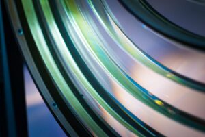 A close-up of a layered glass lens. Photographed in low light, it catches shades of pale green and deep blue.