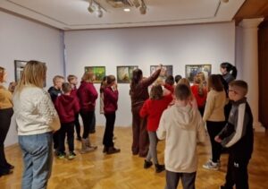 A group of children looking at pictures hung on a white wall