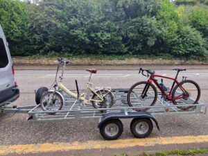 Two bicycles on a trailer hitched to a van.