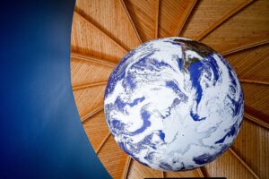 Close-up of a large globe that is suspended from a domed wooden ceiling.