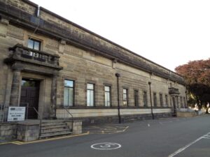 A stone building with a long row of tall windows and a stone porch.