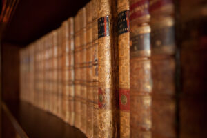 A close up of old books on a shelf. They are gold and brown in colour.